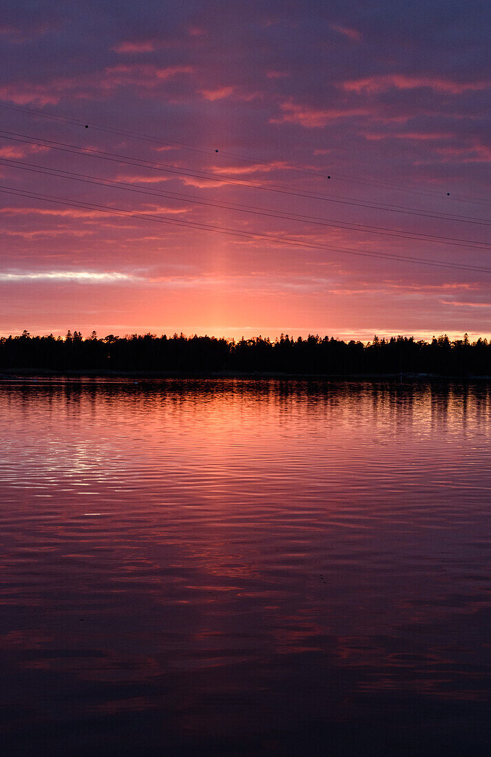 Die Küste der Inseln bei Helsinki, bei Sonnenuntergang, ein rotes Leuchten am Himmel.