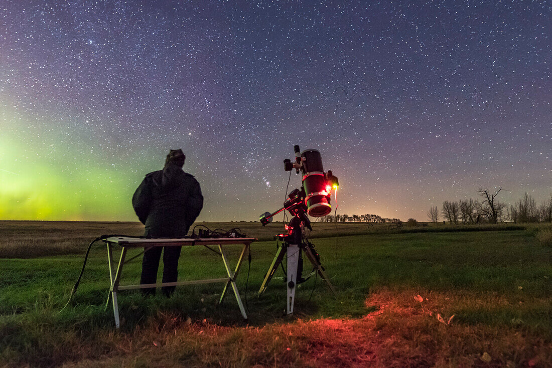 A selfie of me gazing at the sky while the camera and telescope shoot deep-sky targets with the auto-guided equatorial mount and astrographic reflector telescope. An aurora is kicking up to the left in the northeast. Orion is rising at centre in the east. I shot this Thanksgiving evening, October 13m, 2015, from the backyard at home in southern Alberta. It is part of a 730-frame time-lapse.