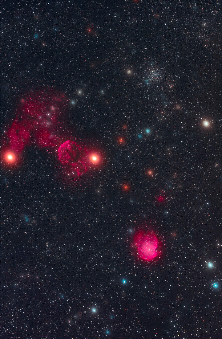 Der Messier-Sternhaufen M35 oben rechts, zusammen mit nahe gelegenen schwachen Nebeln: IC 443, der Nebelbogen links von der Mitte, und NGC 2174 unten rechts, alle in einem sehr farbenfrohen Sternenfeld.