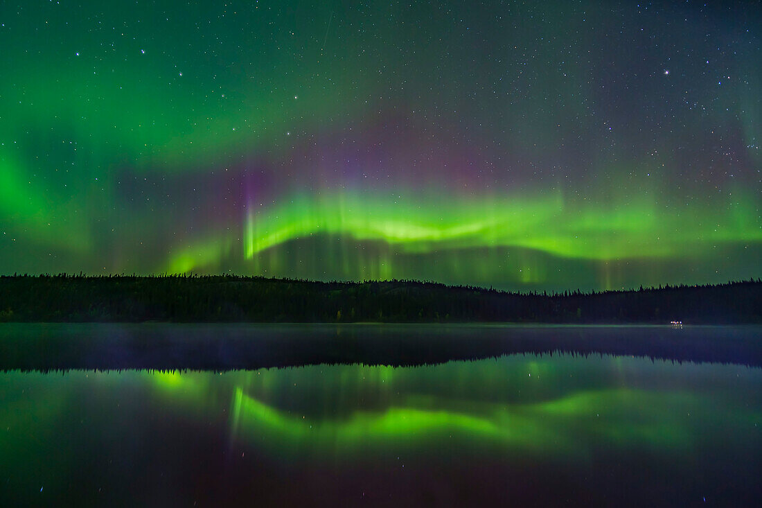 Reflections of the Northern Lights in the calm and misty waters of Madeline Lake on the Ingraham Trail near Yellowknife, NWT on Sept 7, 2019. This is one of a series of “reflection” images. The Big Dipper is at left. Capella is at right. I light painted the mist a little with an LED flashlight.