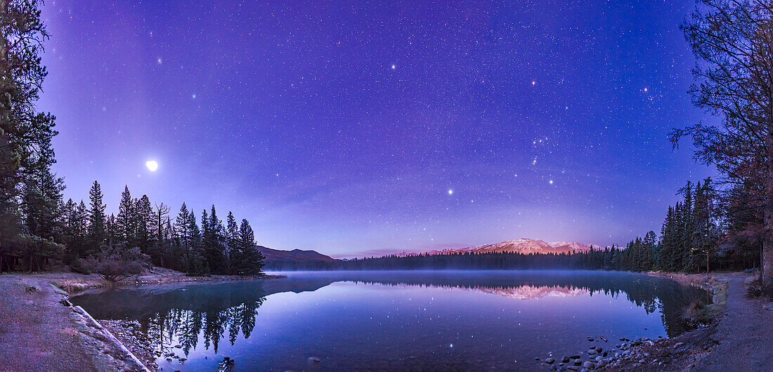 Ein Panorama von etwa 120° zeigt einen stern- und planetenreichen Himmel in der Morgendämmerung über dem Lake Annette im Jasper National Park, Alberta, am Morgen des 25. Oktober 2015.