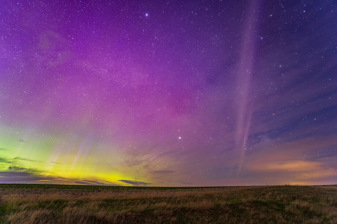 The appearance of the infamous STEVE glowing arc south of the main auroral curtains, on May 27-28, 2022 from home in southern Alberta. This was early on about 11:53 pm MDT as STEVE appeared in his classic mauve colour in the east. STEVE = Strong Thermal Emission Velocity Enhancement, created by hot gas flowing east to west south of the main aurora during an active display. It was Kp5 this night. The main aurora has some subtle blue rays within it at left.