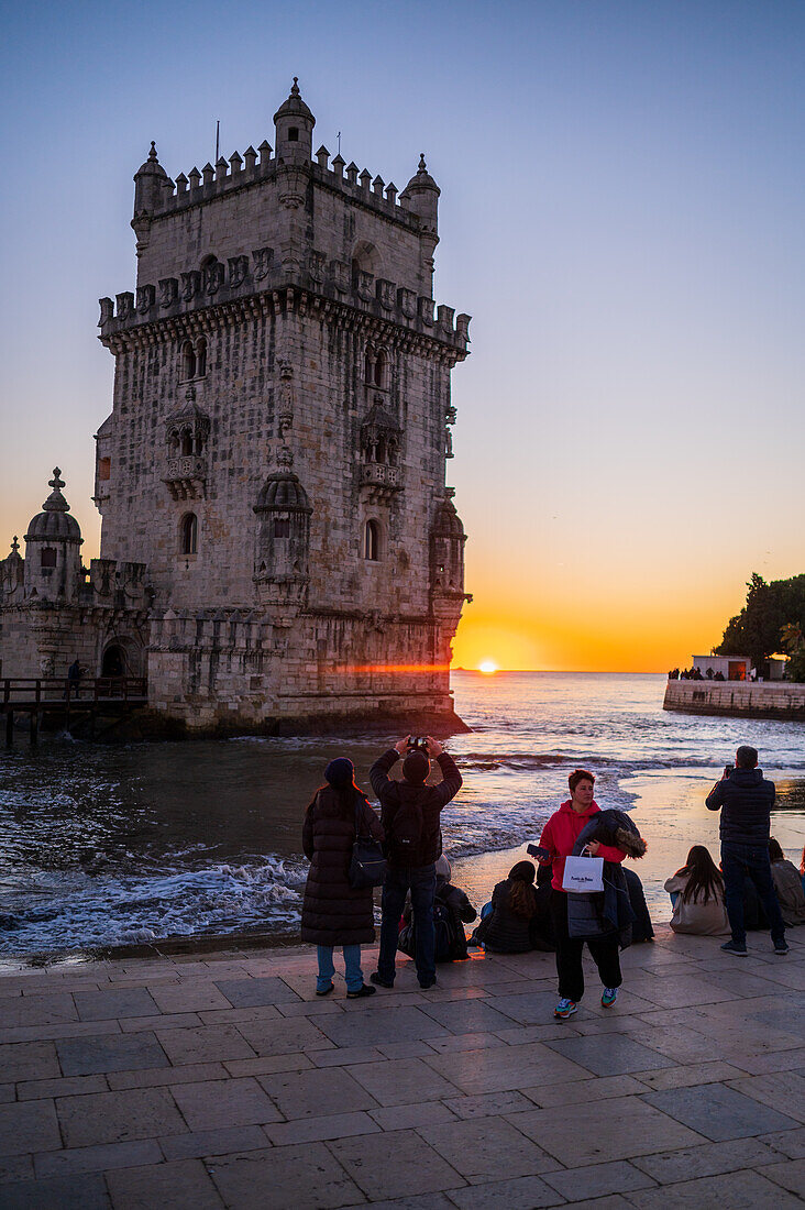 People enjoy a beautiful sunset from Belem Tower or Tower of St Vincent on the bank of the Tagus River, Lisbon, Portugal