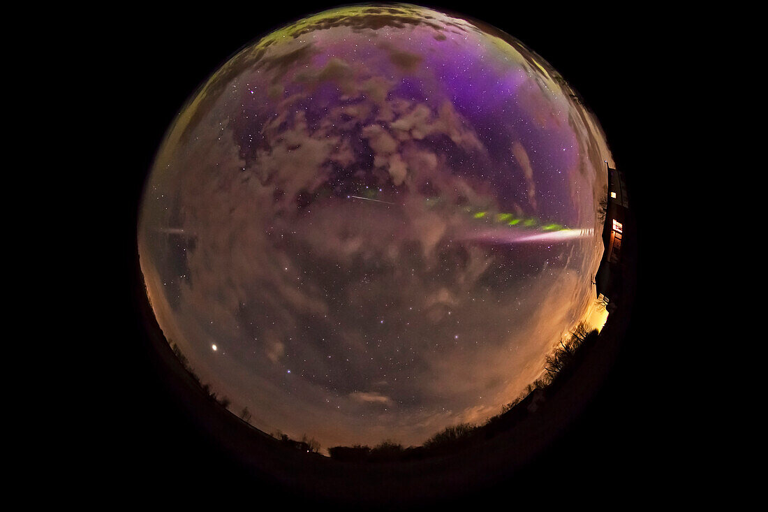 A fish-eye lens / all-sky view of the STEVE aurora arc across the sky and in clouds on May 6, 2018, from home in southern Alberta, with a diffuse aurora to the north casting streaks of purple up the sky, and a green glow along the horizon. This night the aurora was very active to the north and east with a terrific display in Churchill, Manitoba about an hour before this, matching the usual STEVE characteristic of him appearing as a major storm subsides.