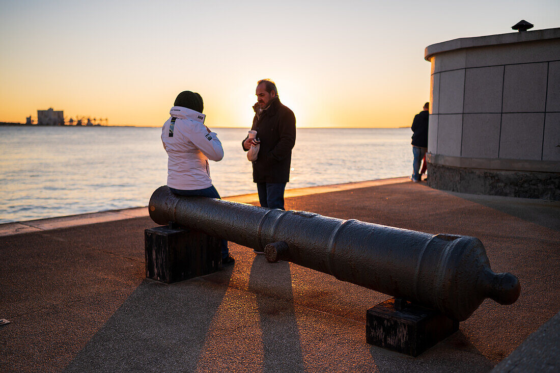 People enjoy a beautiful sunset from Belem Tower or Tower of St Vincent on the bank of the Tagus River, Lisbon, Portugal