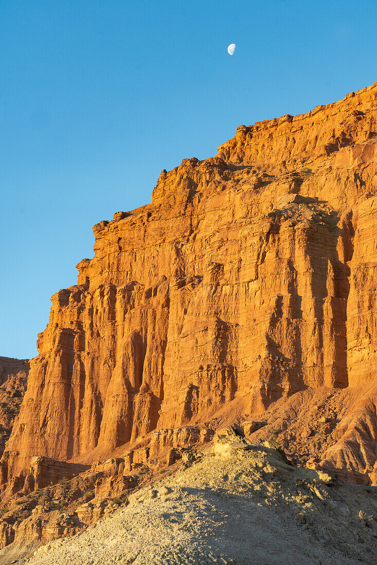 Der Mond über bunten roten Sandsteinfelsen bei Sonnenuntergang im Ischigualasto Provincial Park, Provinz San Juan, Argentinien.