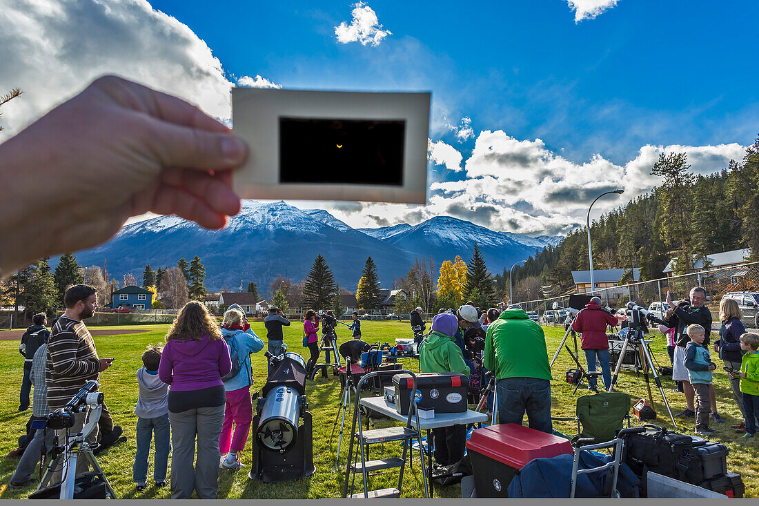 Die partielle Sonnenfinsternis vom 23. Oktober 2014, gesehen von Jasper, Alberta, bei einer öffentlichen Veranstaltung im Centennial Park als Teil des jährlichen Dark Sky Festivals. Es handelt sich um eine Einzelbelichtung, die die Szene in der Mitte der Finsternis mit den Teleskopen von Freiwilligen der Royal Astronomical Society of Canada und den meist klaren Himmel darüber mit der Sonnensichel zeigt, die durch den tragbaren Polymer-Sonnenfilter sichtbar ist.