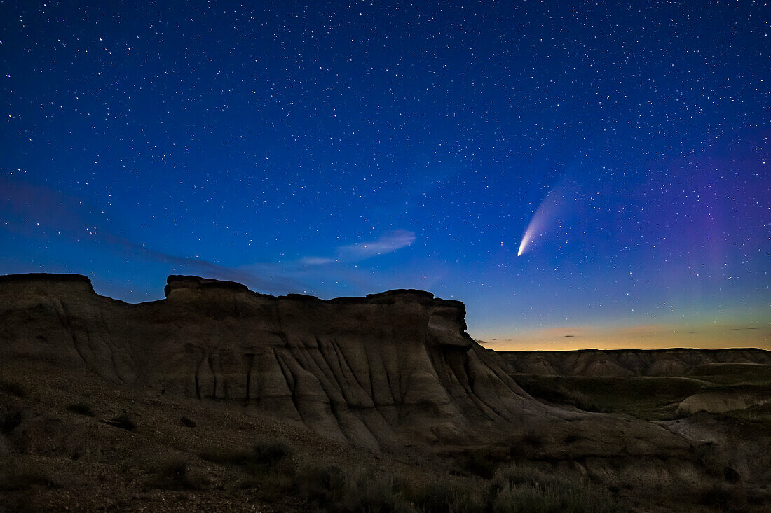 Komet NEOWISE (C/2020 F3) über einigen der erodierten Hoodoo-Formationen im Dinosaur Provincial Park, Alberta, 14. und 15. Juli 2020. Rechts ist ein schwaches Polarlicht zu sehen. Der Vordergrund ist nur durch Sternenlicht beleuchtet; hier wurde keine Lichtmalerei verwendet.