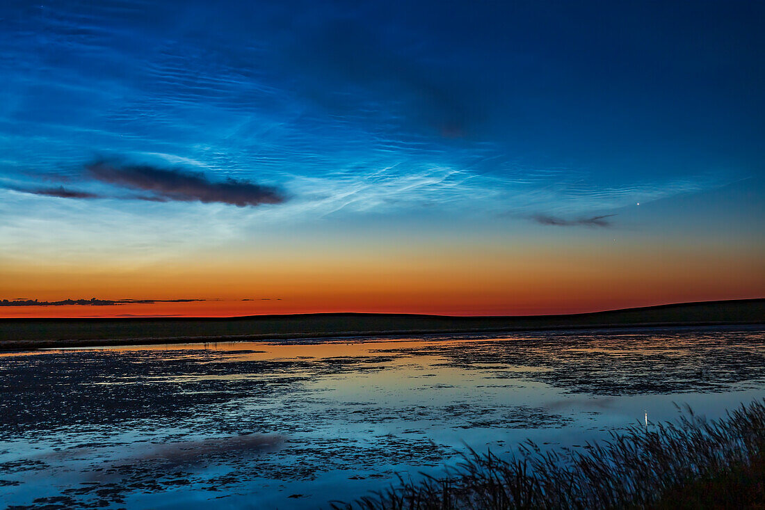 A single image of bright noctilucent clouds in the dawn sky over a prairie pond near home in southern Alberta on July 7, 2020, with Venus bright as a “morning star” at right above Aldebaran. Comet NEOWISE was in the scene but hidden behind dark weather clouds here.
