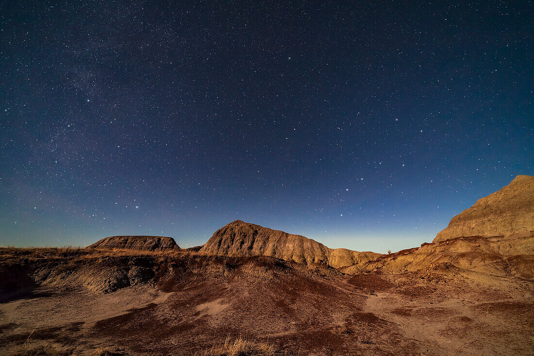 The northern circumpolar sky with the Big Dipper at right rising, and Deneb in Cygnus and Vega in Lyra at left settting, over the moonlit badland hills of Dinosaur Provincial Park, Alberta, on November 27, 2017. The Dipper points up to Polaris and the Little Dipper. The Moon was a day past first quarter. Polaris and the Little Dipper are at centre, so this is looking north to the circumpolar sky.