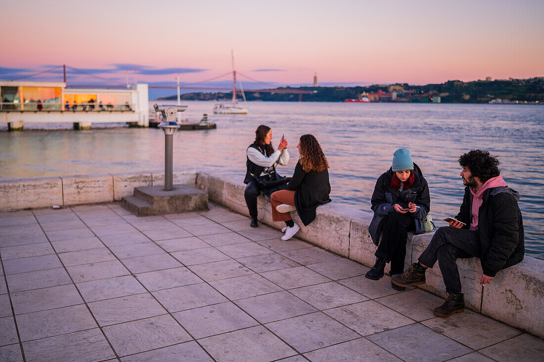 People enjoying the sunset in Belem promenade by Tagus River, Lisbon, Portugal