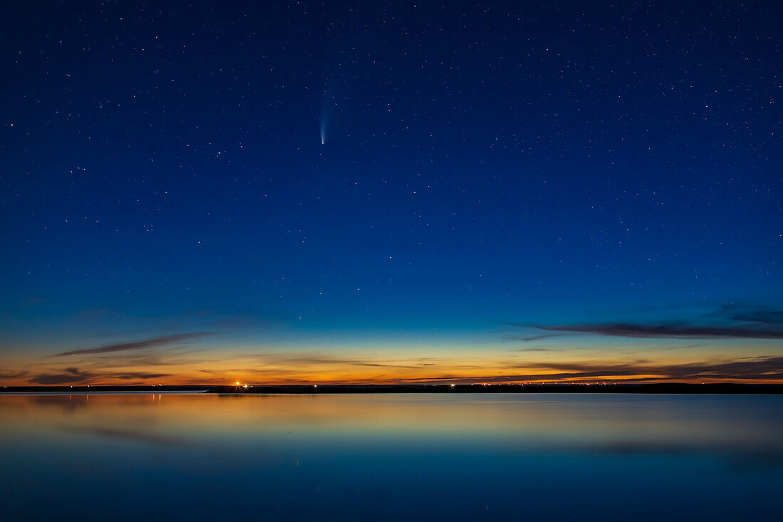 Komet NEOWISE (C/2020 F3) über dem stillen Wasser des Crawling Lake in Süd-Alberta. Dies war am frühen Abend, als der Himmel noch in der Dämmerung hell gefärbt war. Der Komet befand sich im südlichen Teil von Ursa Major zwischen den Sternenpaaren Tania und Talitha. Die vorhandenen Wolken bildeten einen schönen Rahmen für die Szene und spiegelten sich auch im Wasser. Der Komet war zu hoch, um zu diesem Zeitpunkt als Reflexion sichtbar zu sein.