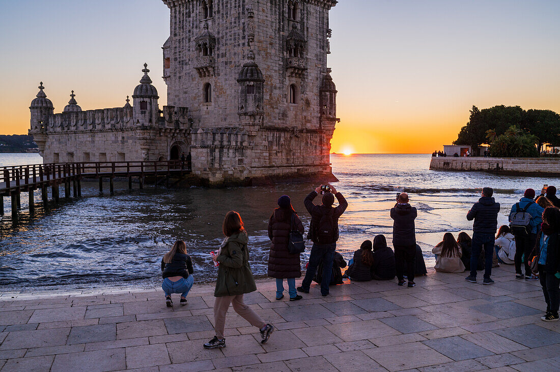 People enjoy a beautiful sunset from Belem Tower or Tower of St Vincent on the bank of the Tagus River, Lisbon, Portugal