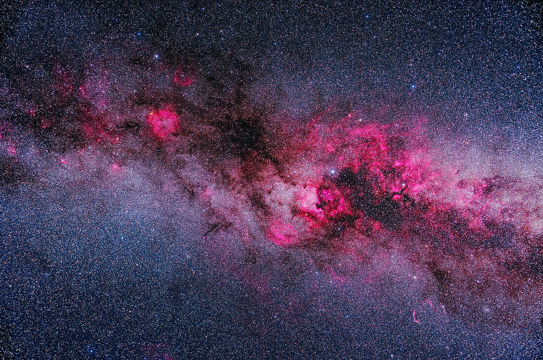 A framing of the major areas of bright and dark nebulosity in Cygnus and Cepheus, showing pink emission nebulas contrasting with dark dusty regions in the Cygnus and into the Perseus arms of the Milky Way. Cepheus is at upper left; northern Cygnus is at right, with the bright Cygnus starcloud right of centre. The reddening (or yellowing) effects of interstellar dust in the spiral arms of the Milky Way is apparent.