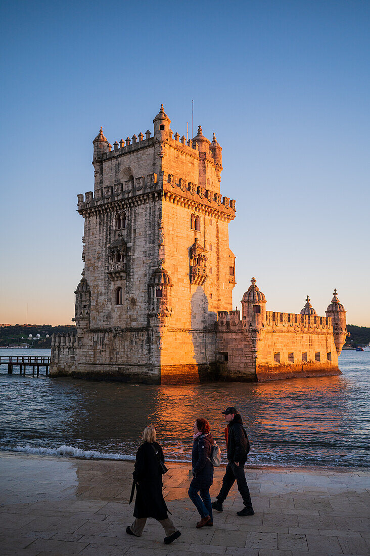 People enjoy a beautiful sunset from Belem Tower or Tower of St Vincent on the bank of the Tagus River, Lisbon, Portugal