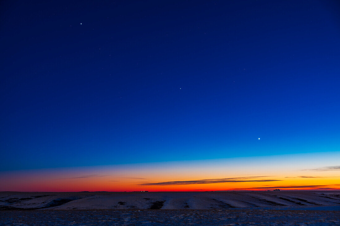 The line-up of three evening planets in the southwest twilight sky, on December 17, 2021 — with Jupiter at top left, Venus at bottom right, and dimmer Saturn in the middle, all defining the line of the ecliptic in the cold winter sky this night. The stars of Capricornus are at centre.