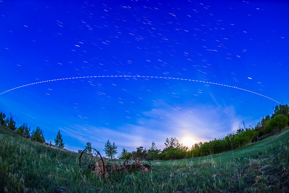 A pass of the International Space Station in the brightening twilight of dawn, on the morning of June 1, 2015, with the gibbous Moon setting to the southwest at right. The view is looking south, with the ISS travelling from right (west) to left (southeast) over several minutes. This was the last pass of a 4-pass night, May 31/June 1, starting at 3:55 am MDT this morning.