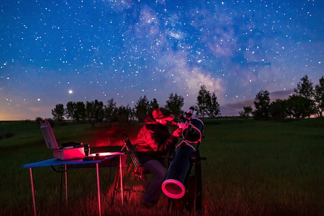 A selfie of me observing with the 20cm Sky-Watcher Dobsonian telescope on a June night in the backyard. Shot for a book illustration of accessories and observing. The sky is blue from solstice twilight as this was June 18, 2020. The galactic core is at centre; Jupiter is rising at left.