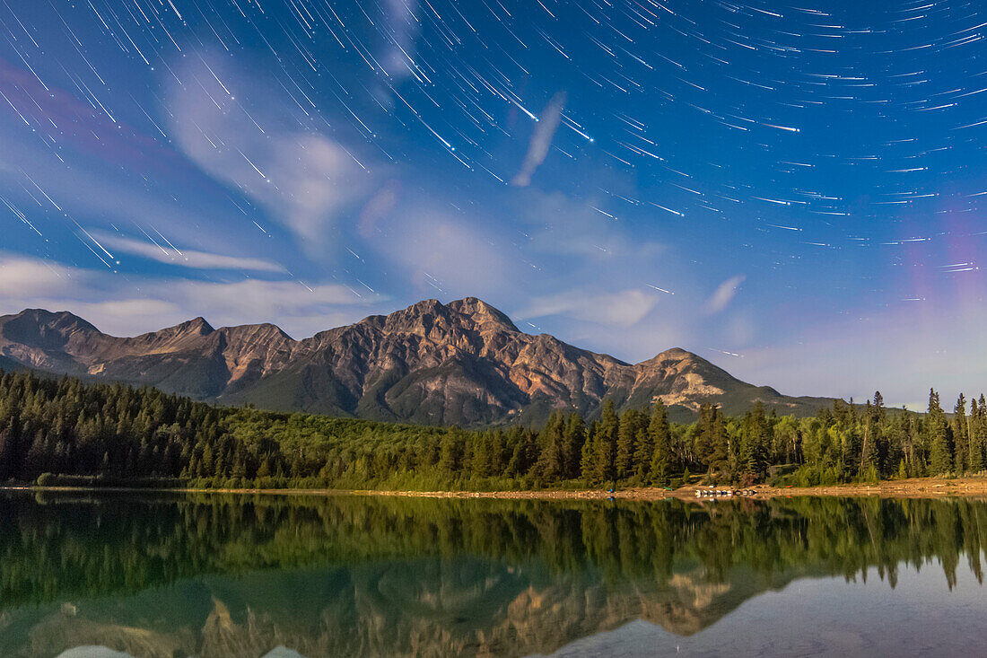 Star trails over Patricia Lake and Pyramid Mountain in Jasper National Park. Moonlight provides the illumination and a faint aurora is at lower right in the northeast. The Big Dipper is the main pattern right of centre.