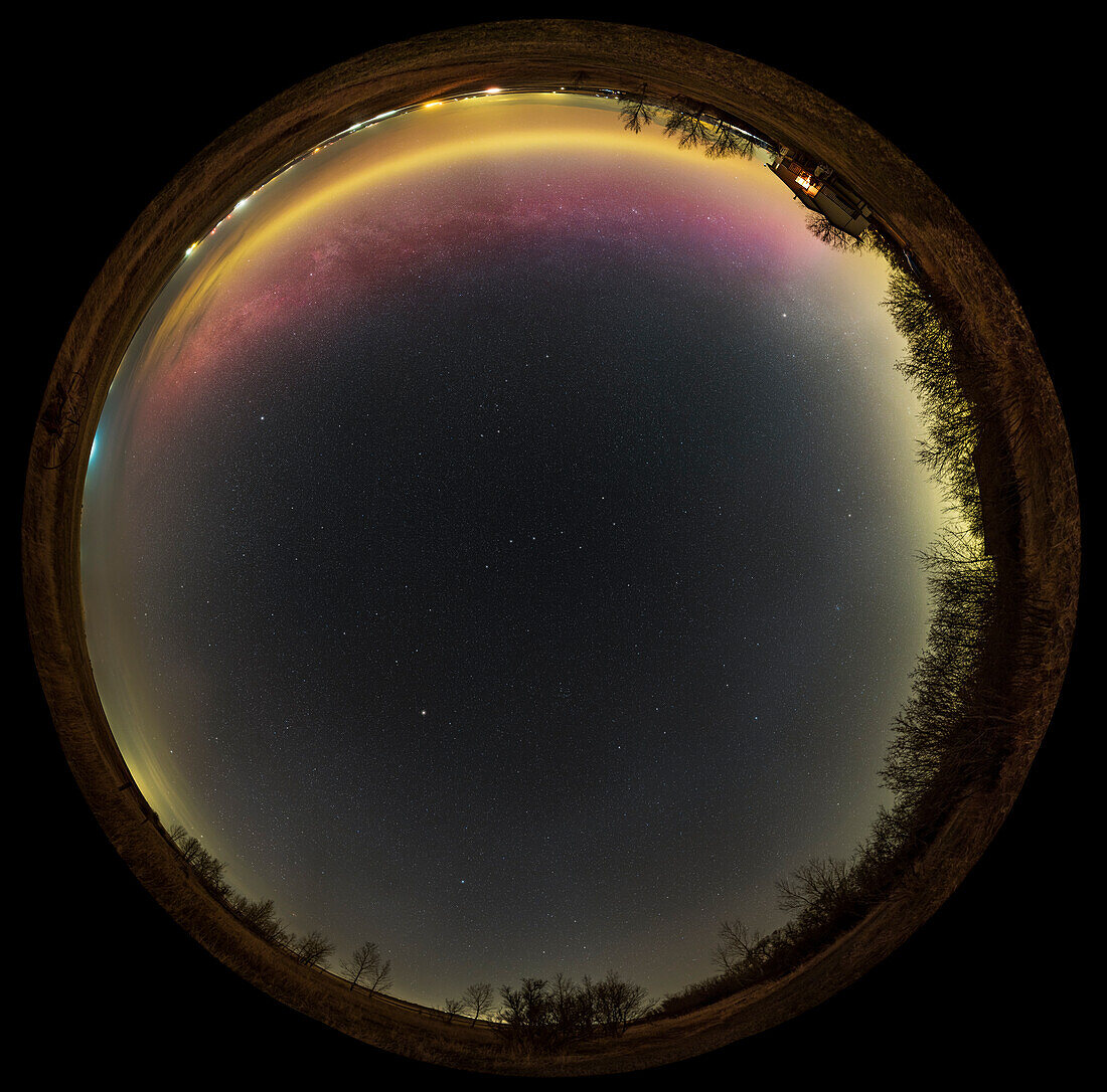 Ein 360° "all-sky" Panorama des nördlichen Frühlingshimmels, aufgenommen, als der galaktische Nordpol fast genau südlich hoch am Himmel stand, so dass wir aus der Ebene unserer Galaxie nach oben schauen. Die Milchstraße ist zwar sichtbar, aber nur als ein tiefer Bogen über dem Norden, und in dieser Nacht (27. April 2022) fiel ein Bogen eines schwachen grünen und magentafarbenen Polarlichts genau mit der Position der Milchstraße zusammen. Der galaktische Nordpol befindet sich gleich links neben dem Coma Berenices-Sternhaufen unterhalb der Mitte.