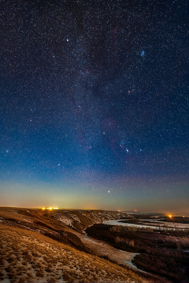 Orion and the winter stars and constellations rising in the light of a first quarter Moon on December 3, 2019. The vertical format sweeps up the Milky Way.