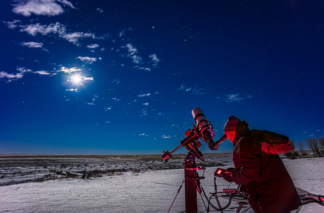 A selfie of me observing Mars, the bright object at top, in Taurus, on a mild winter night from home on December 9, 2022. Mars was then two days past opposition and at its brightest. The waning gibbous Moon is the bright glow at left, lighting the sky blue and the snowy landscape below with sparkling moonlight. Orion is rising behind me, while Gemini is at far left.