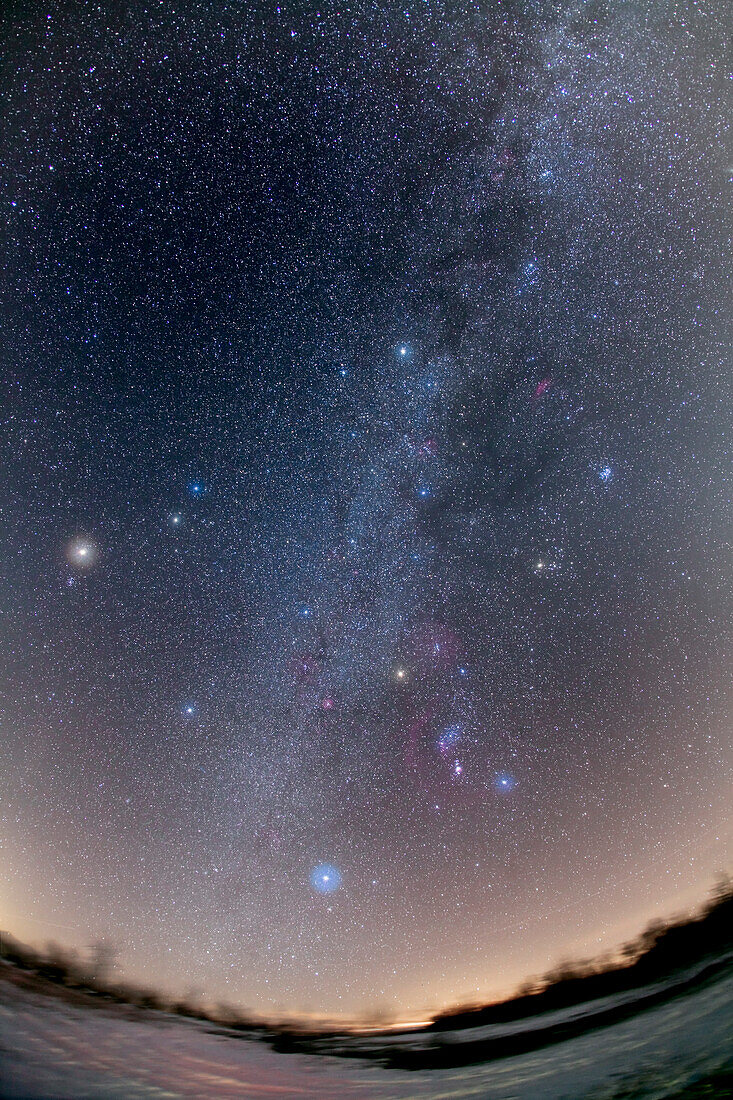 Horizon-to-zenith panorama of the northern winter sky, from Canis Major in the south just above the horizon to Cassiopeia past the zenith at the top of the frame. Capella is near the zenith above centre. The extra star at left is Mars, just 10 days past opposition, on Feb. 9, 2010, when it was just above the Beehive star cluster. Taken with Canon 5DMkII and Canon 15mm lens, at f/5 for stack of 3 exposures x 4.5 minutes each at ISO 800. Two exposures had frost on the lens, thus the big star haloes. Taken from southern Alberta, Canada.