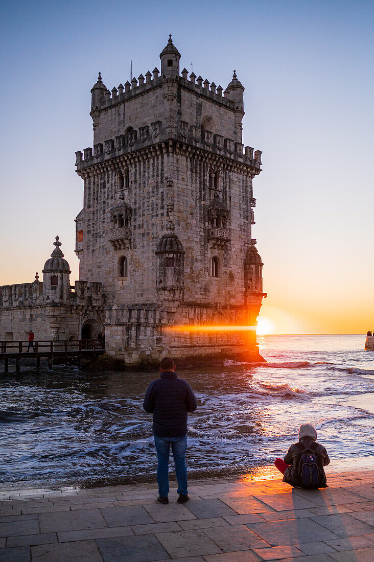 People enjoy a beautiful sunset from Belem Tower or Tower of St Vincent on the bank of the Tagus River, Lisbon, Portugal