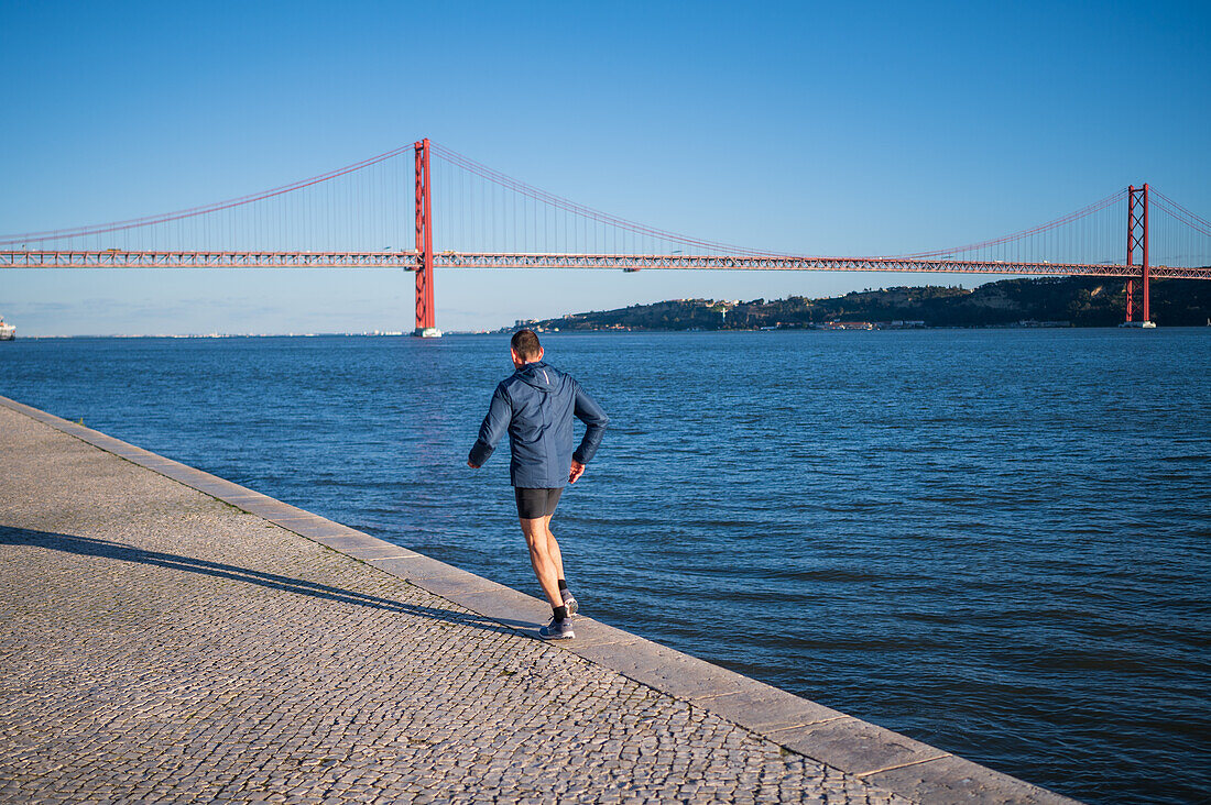 Runner and Ponte 25 de Abril bridge, Belem, Lisbon, Portugal