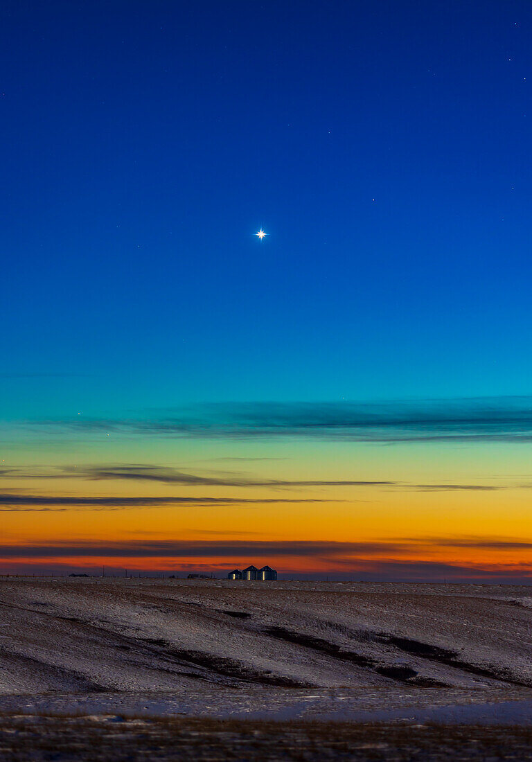 Venus in der Abenddämmerung am 17. Dezember 2021, etwa 2 Wochen nach dem Zeitpunkt ihres größten Glanzes. Diese Aufnahme entstand in der Hoffnung, auch den Kometen Leonard zu erwischen, aber er war nur ein schwacher Fleck, der sich kaum vom Hintergrundhimmel abhob und hier hinter einer dünnen Wolke liegt. Die Aufnahme entstand in der Nähe meines Hauses in Süd-Alberta. Die Beleuchtung des Vordergrunds stammt vom Gibbous-Mond im Nordosten gegenüber dieser Szene, die nach Südwesten zeigt.