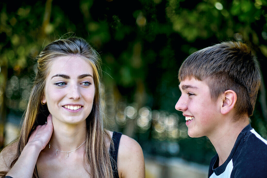 Portrait of a young caucasian woman with her brother posing outdoor in a garden. Lifestyle concept.