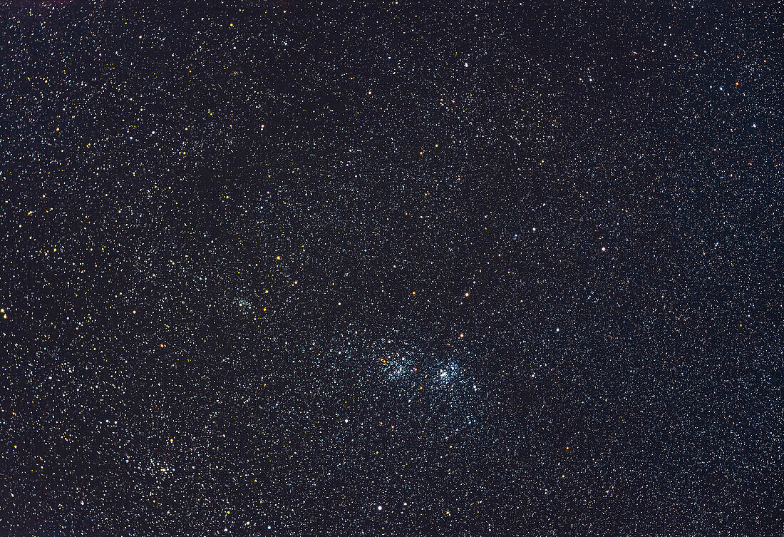 Der berühmte Doppelsternhaufen (NGC 869, rechts und NGC 884, links) im Perseus, in einer Weitfeldaufnahme, die auch die nahe gelegenen Sternhaufen NGC 957 links und Trumpler 2 unten links einschließt. Der große und spärliche Sternhaufen Stock 2, auch bekannt als Muskelmann-Haufen, befindet sich oben rechts. Das Feld ist mit gelben Überriesensternen gefüllt. Das Gesichtsfeld ist ähnlich dem eines Fernglases.