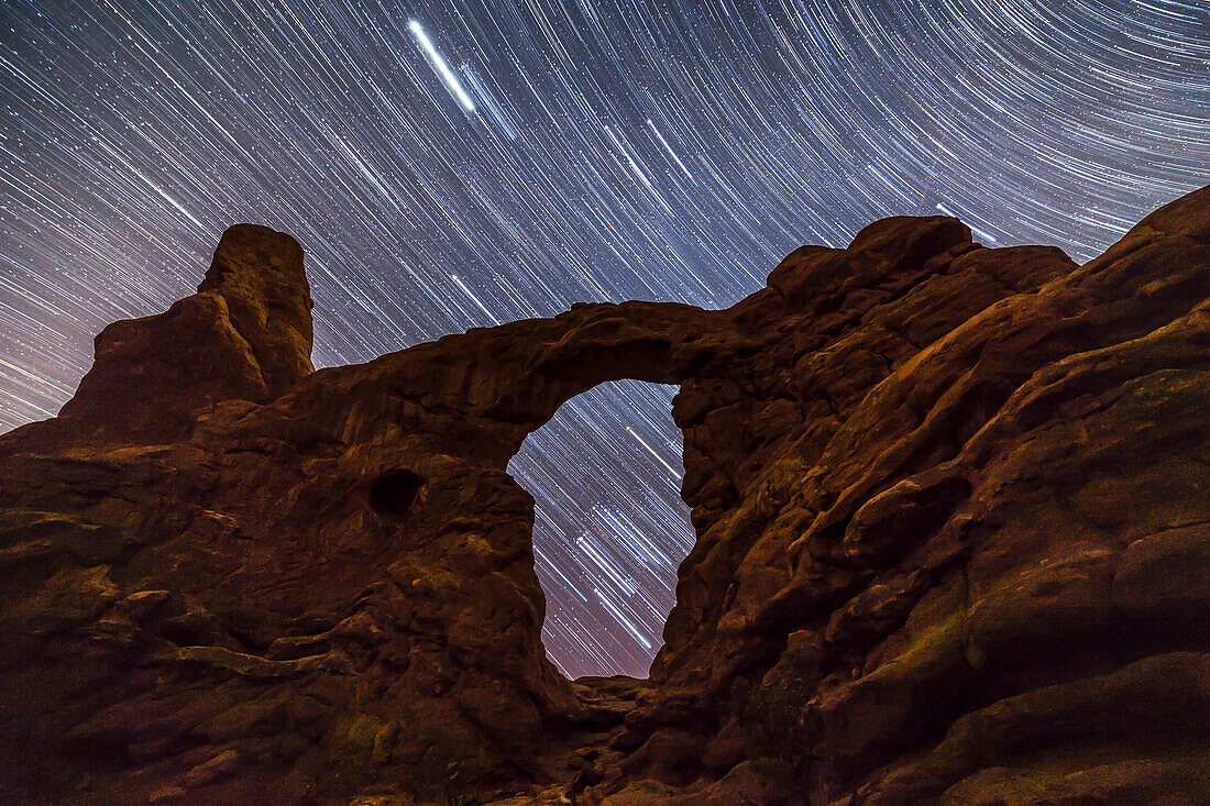 Orion and the stars of the winter sky trailing as they set behind and through Turret Arch, in Arches National Park, Utah. I shot this April 6, 2015 after twilight but before the waning Moon rose, so the sky was dark. Illumination is from stars and the sky – no artificial light provided, and the Moon was not up.