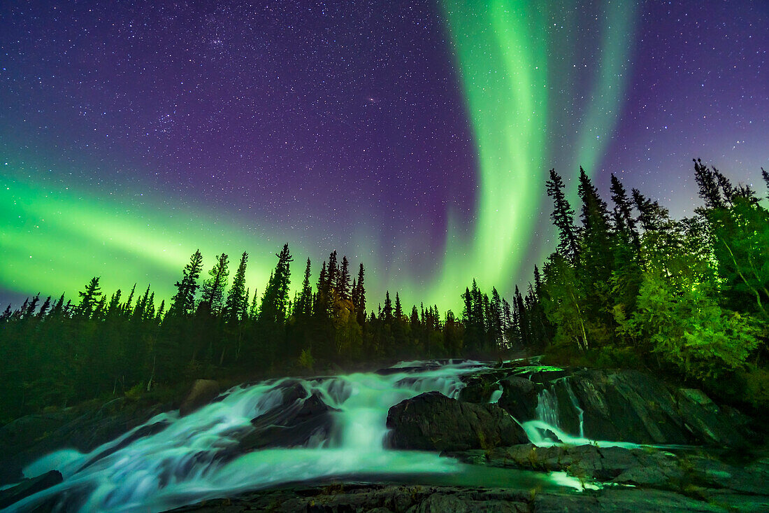 The Northern Lights over the waterfalls known as the Ramparts on the Cameron River east of Yellowknife, NWT, on September 8, 2019. The aspen trees are turning yellow on this September evening. This is looking northeast toward Perseus and Andromeda. M31 is at top centre.