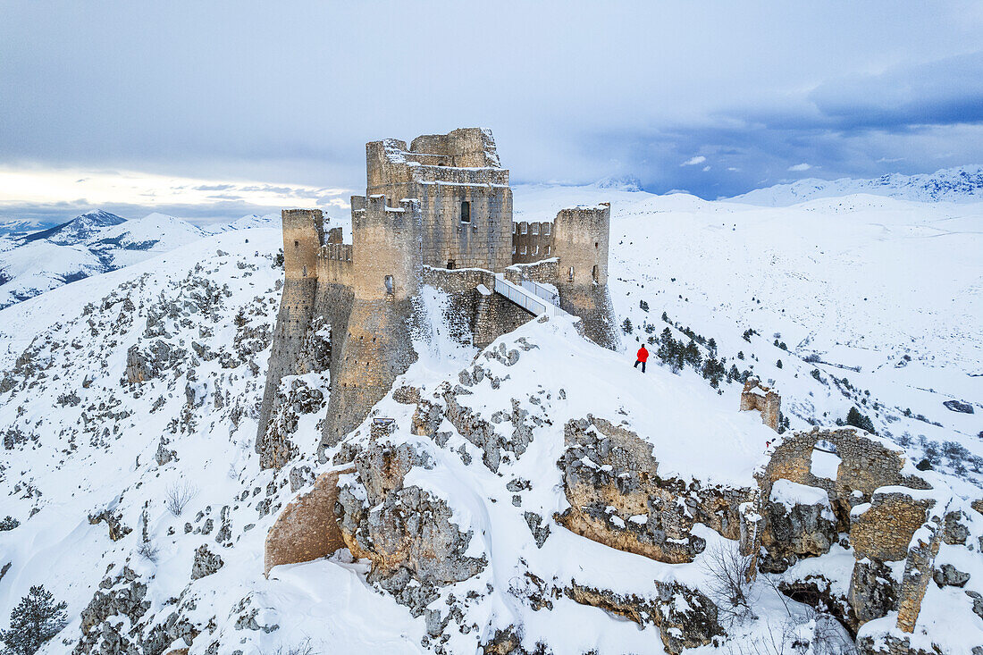 Man admiring the snowy medieval castle of Rocca Calascio after heavy snowfall, Rocca Calascio, Gran Sasso and Monti della Laga National Park, L'Aquila province, Abruzzo region, Apennines, Italy, Europe