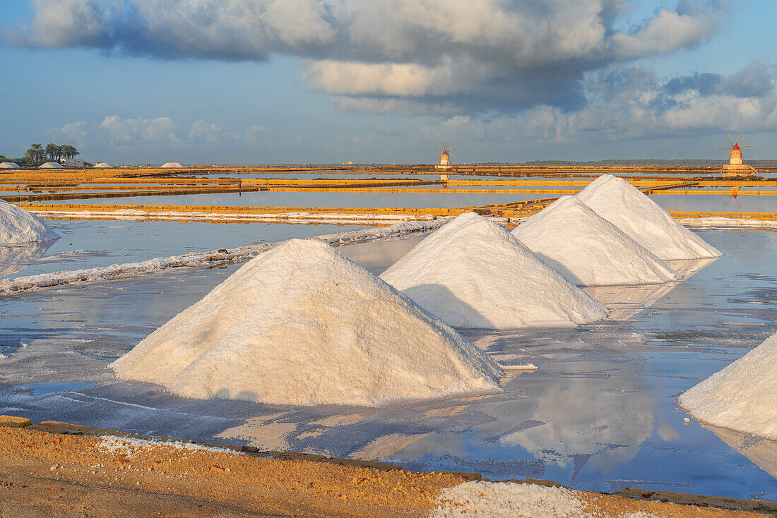 Salzhaufen zwischen Salinen mit Windmühlen im Hintergrund bei Sonnenuntergang, Saline Ettore e Infersa, Marsala, Provinz Trapani, Sizilien, Italien, Mittelmeer, Europa