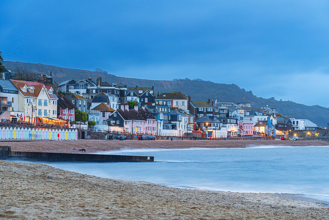 Blick vom Strand auf das farbenfrohe Dorf Lyme Regis in der Abenddämmerung, Jurassic Coast, UNESCO Weltkulturerbe, Dorset, England, Vereinigtes Königreich, Europa