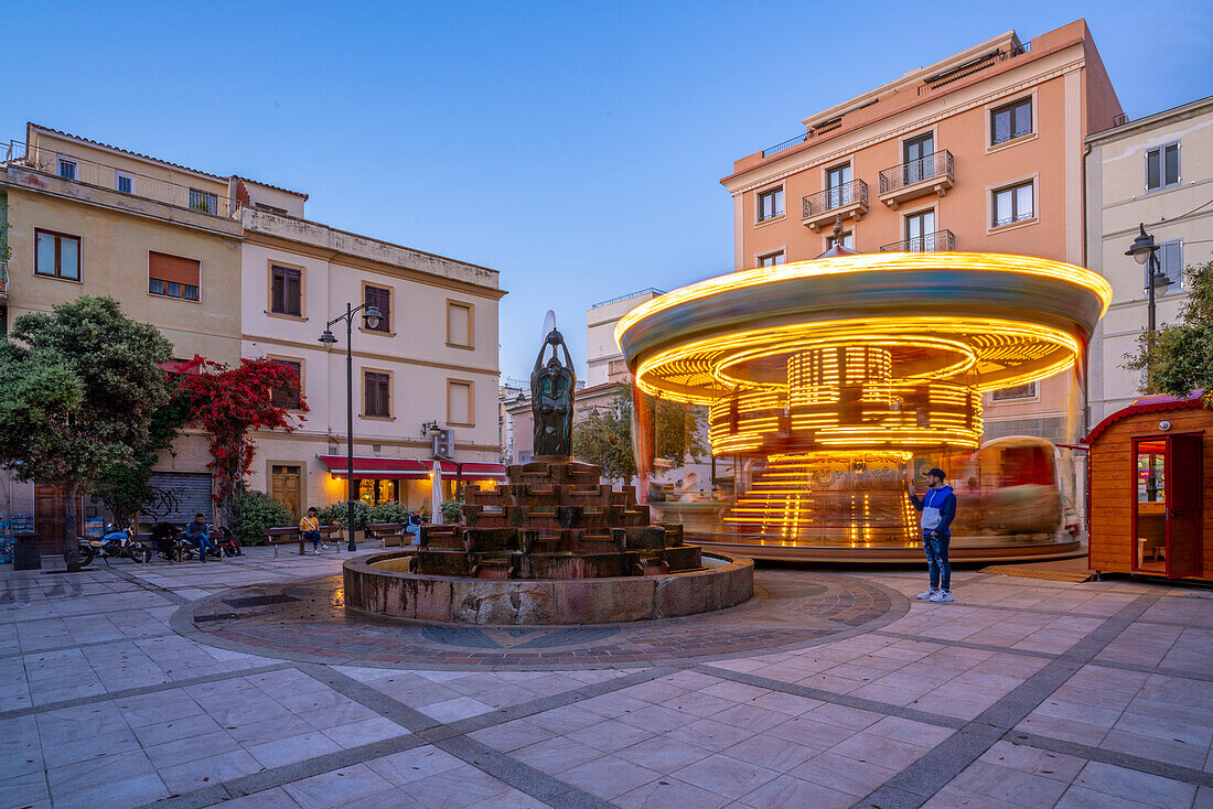 Blick auf Karussell und Springbrunnen auf der Piazza Matteotti in der Abenddämmerung, Olbia, Sardinien, Italien, Mittelmeer, Europa