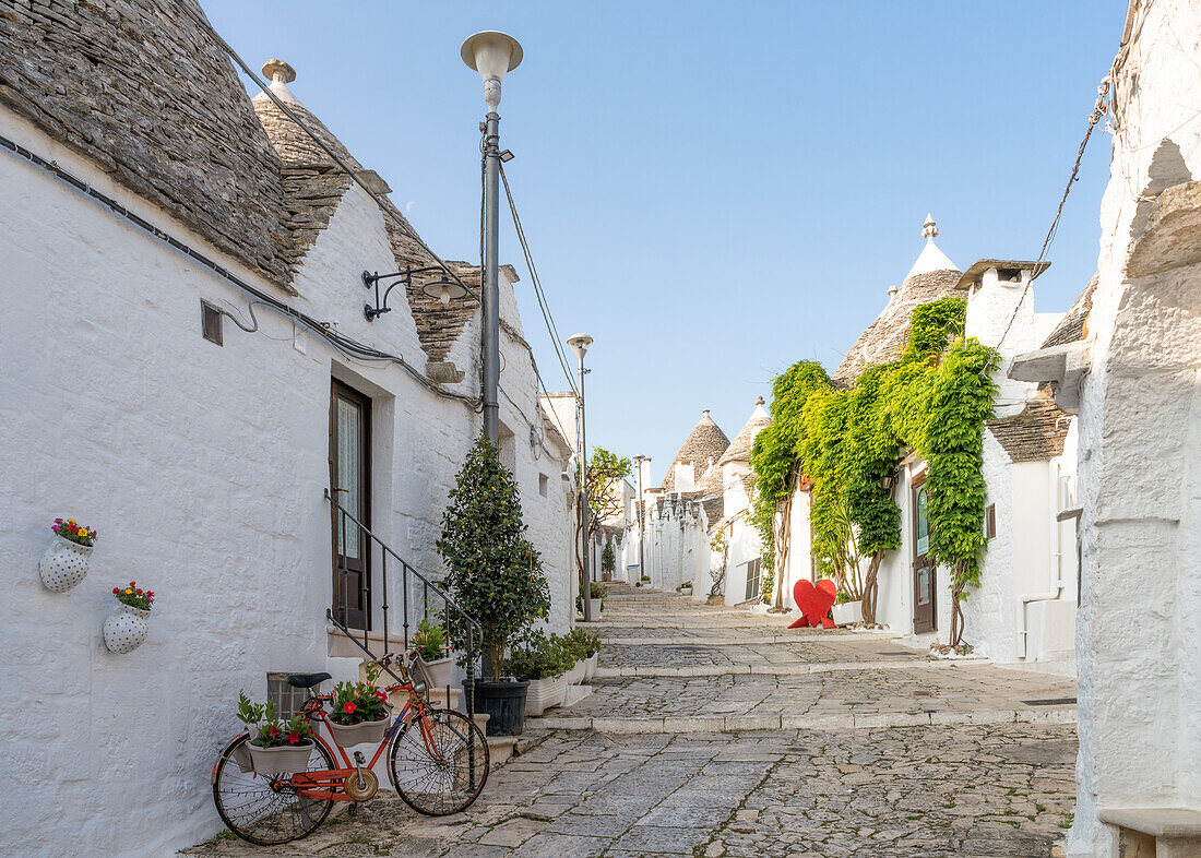 Weiß getünchte Trulli-Häuser entlang einer Straße in der Altstadt, UNESCO-Weltkulturerbe, Alberobello, Apulien, Italien, Europa