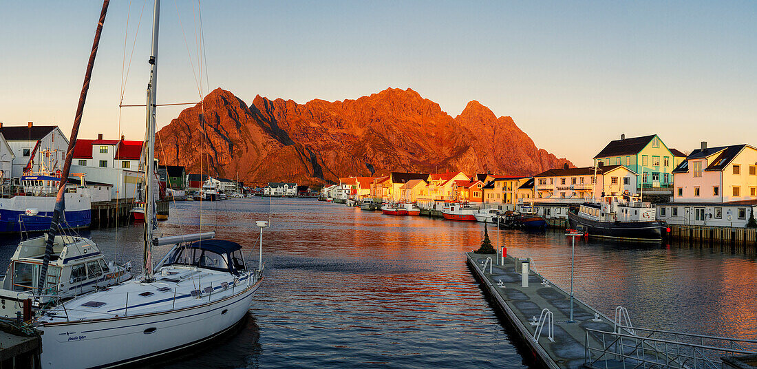 Hafen und Dorf Henningsvaer bei Sonnenuntergang mit Bergen im Hintergrund, Bezirk Nordland, Lofoten, Norwegen, Skandinavien, Europa