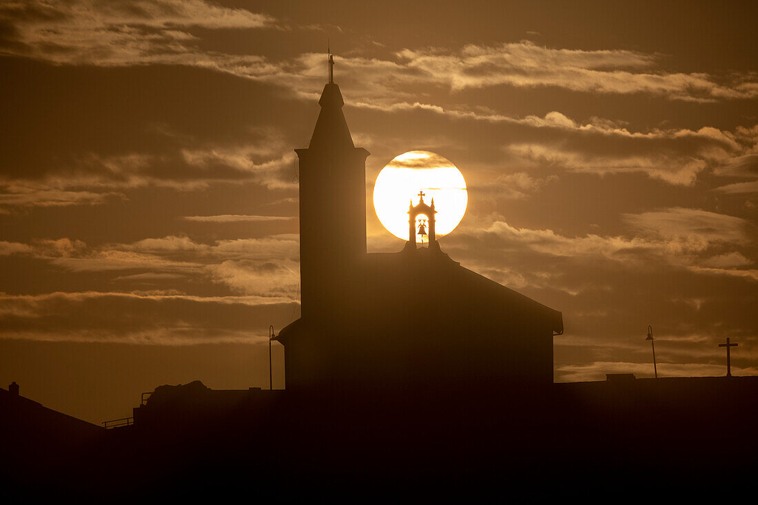 Die Sonne im Einklang mit der Silhouette der Kirche von Luarca, Asturien, Spanien, Europa