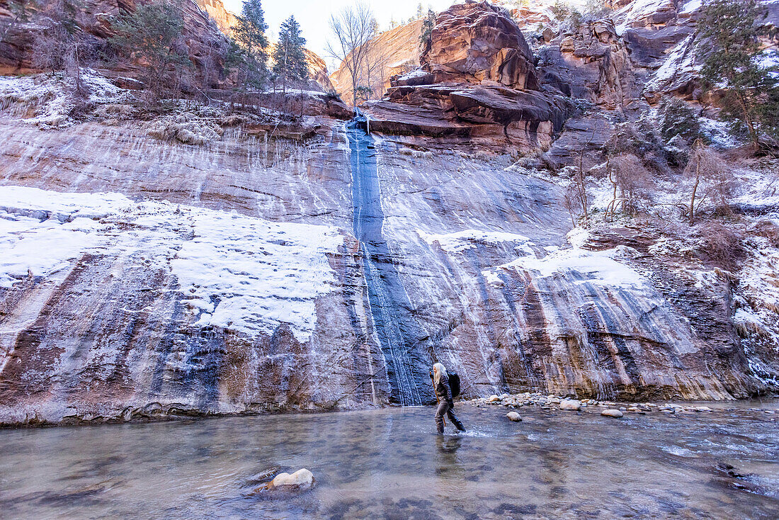 USA, Utah, Springdale, Zion National Park, Senior woman crossing river while hiking in mountains