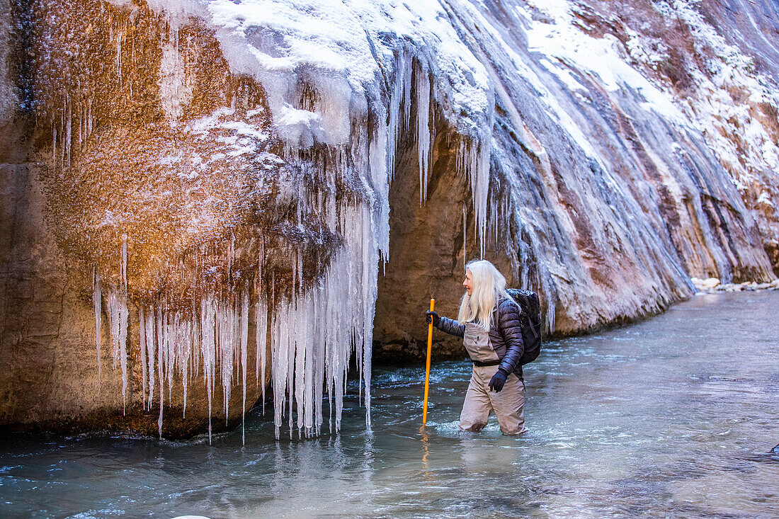 USA, Utah, Springdale, Zion National Park, Ältere Frau überquert Fluss beim Wandern in den Bergen