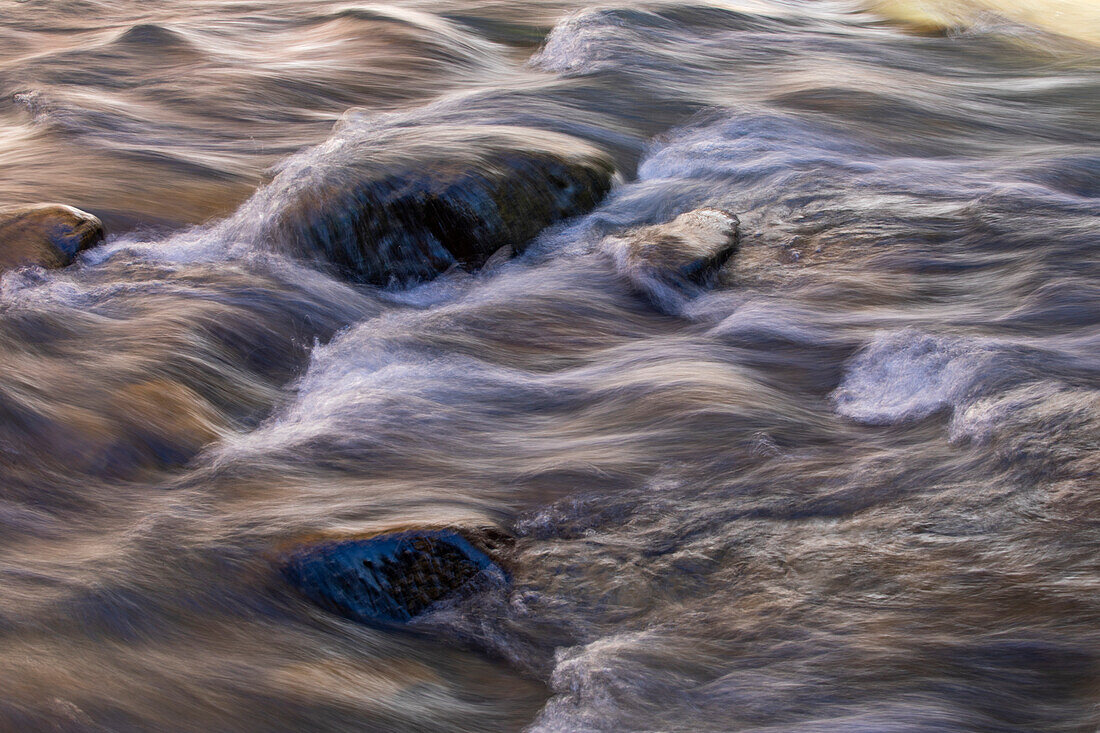 Unscharfes Bild von Wasser, das auf Steine läuft