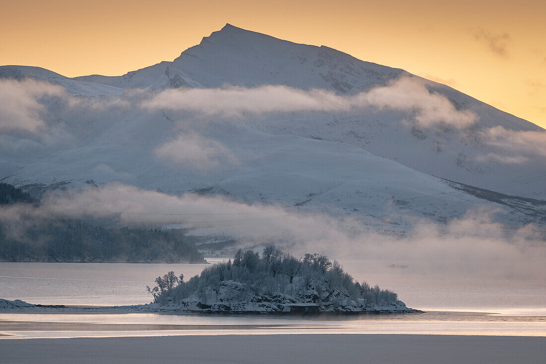 Holman Island im Ramfjorden mit dem Gipfel des Haugafjellet im Hintergrund bei Sonnenuntergang, nahe Tromso, Troms og Finnmark, Norwegen, Skandinavien, Europa