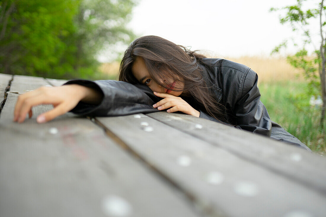 Portrait of teenage girl (16-17) leaning on picnic table