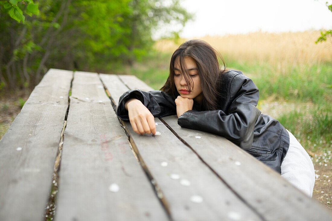 Portrait eines Mädchens im Teenageralter (16-17), das sich an einen Picknicktisch lehnt