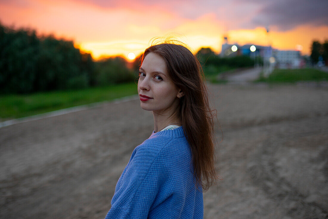 Portrait of beautiful woman standing in field at sunset