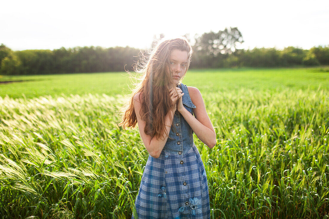 Portrait of woman standing with hands clasped in field