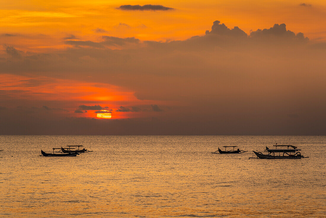 Blick auf Sonnenuntergang und Fischerboote am Indischen Ozean vom Kuta Beach aus, Kuta, Bali, Indonesien, Südostasien, Asien